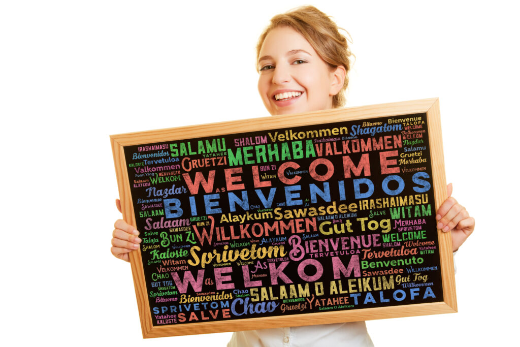 Frau hält Tafel mit dem Wort "Willkommen" in verschiedenen Sprachen